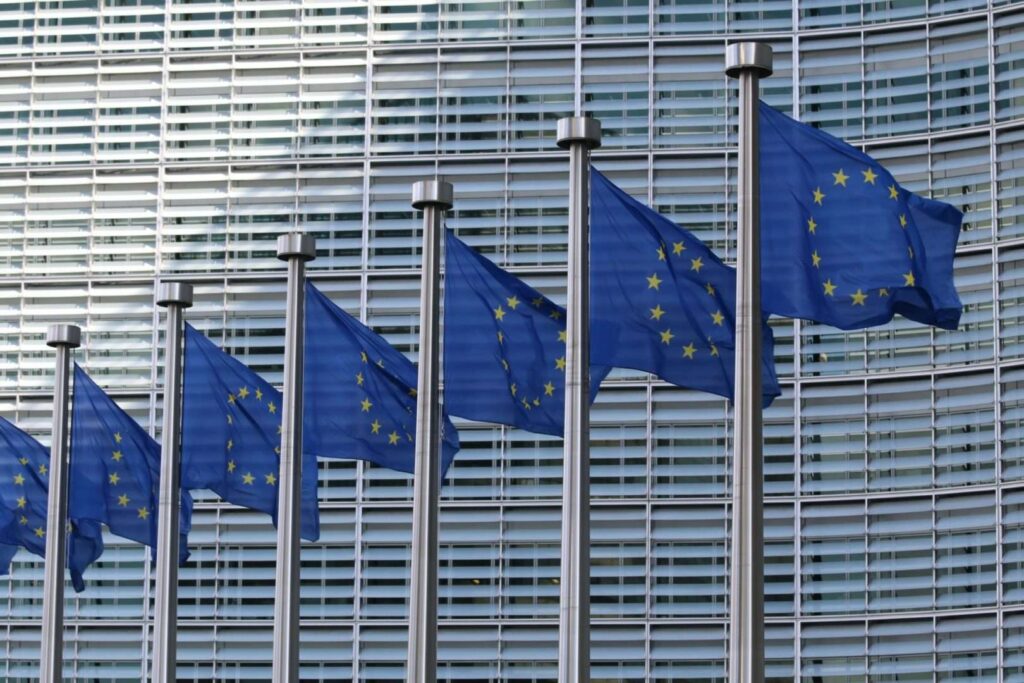 EU flags waving in front of an office building, representing European Union unity and governance.